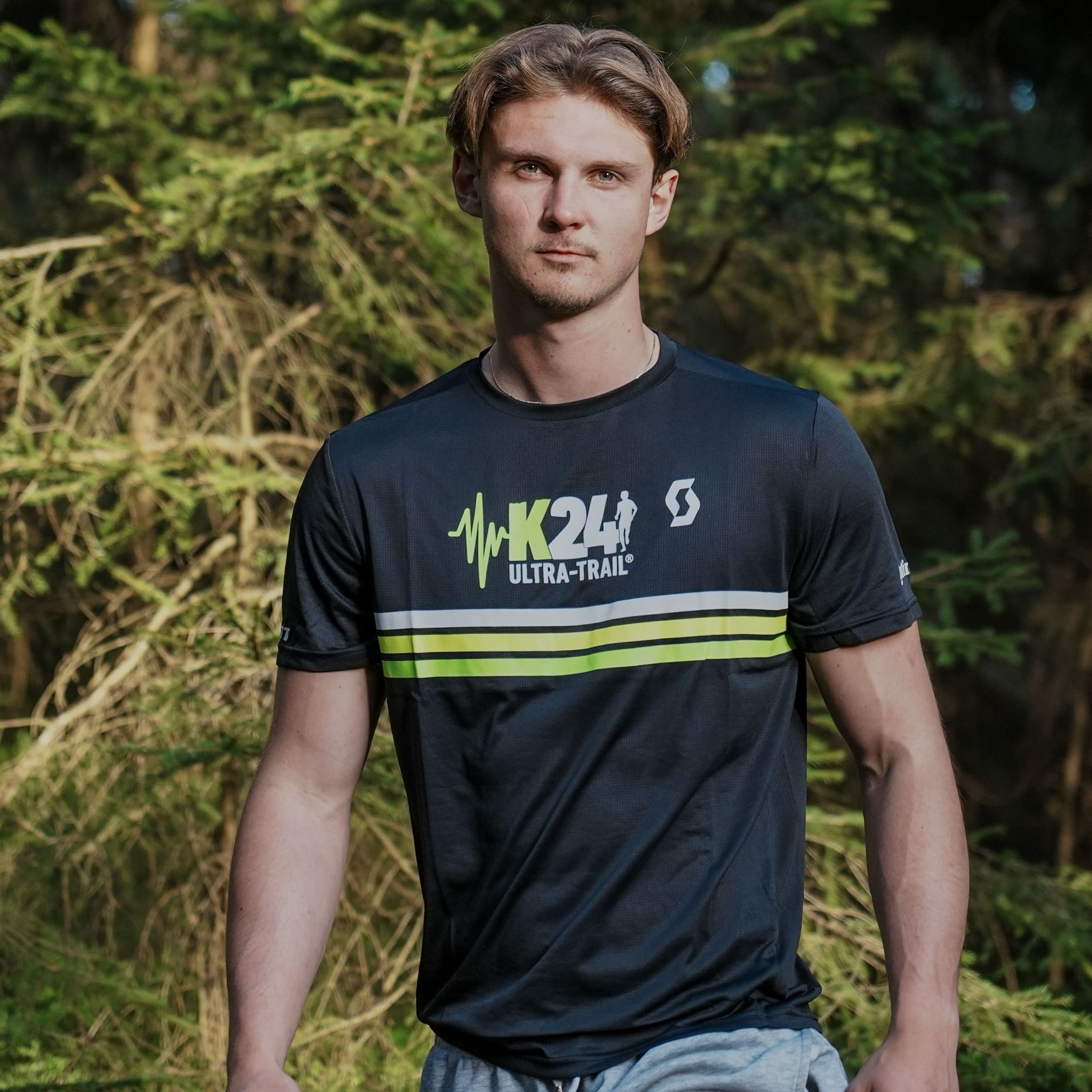 Man wearing a black sports t-shirt with visible branding in a forest setting