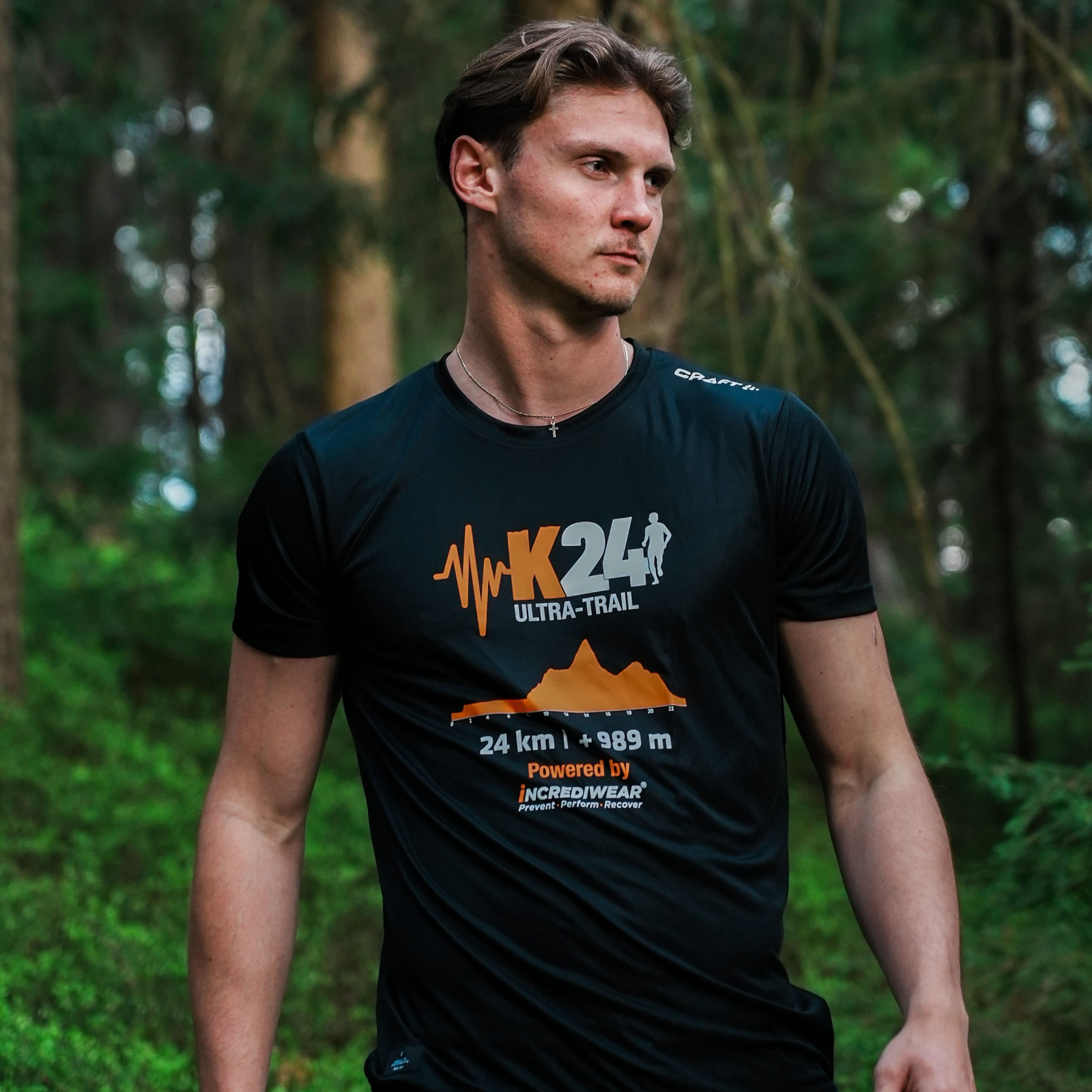 Man wearing a black t-shirt with K24 Ultra-Trail branding in a forest setting