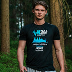 Man wearing a black t-shirt with blue and white graphics and text, standing in a forest.