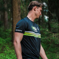 Man wearing a sports jersey with brand logos in a forest setting