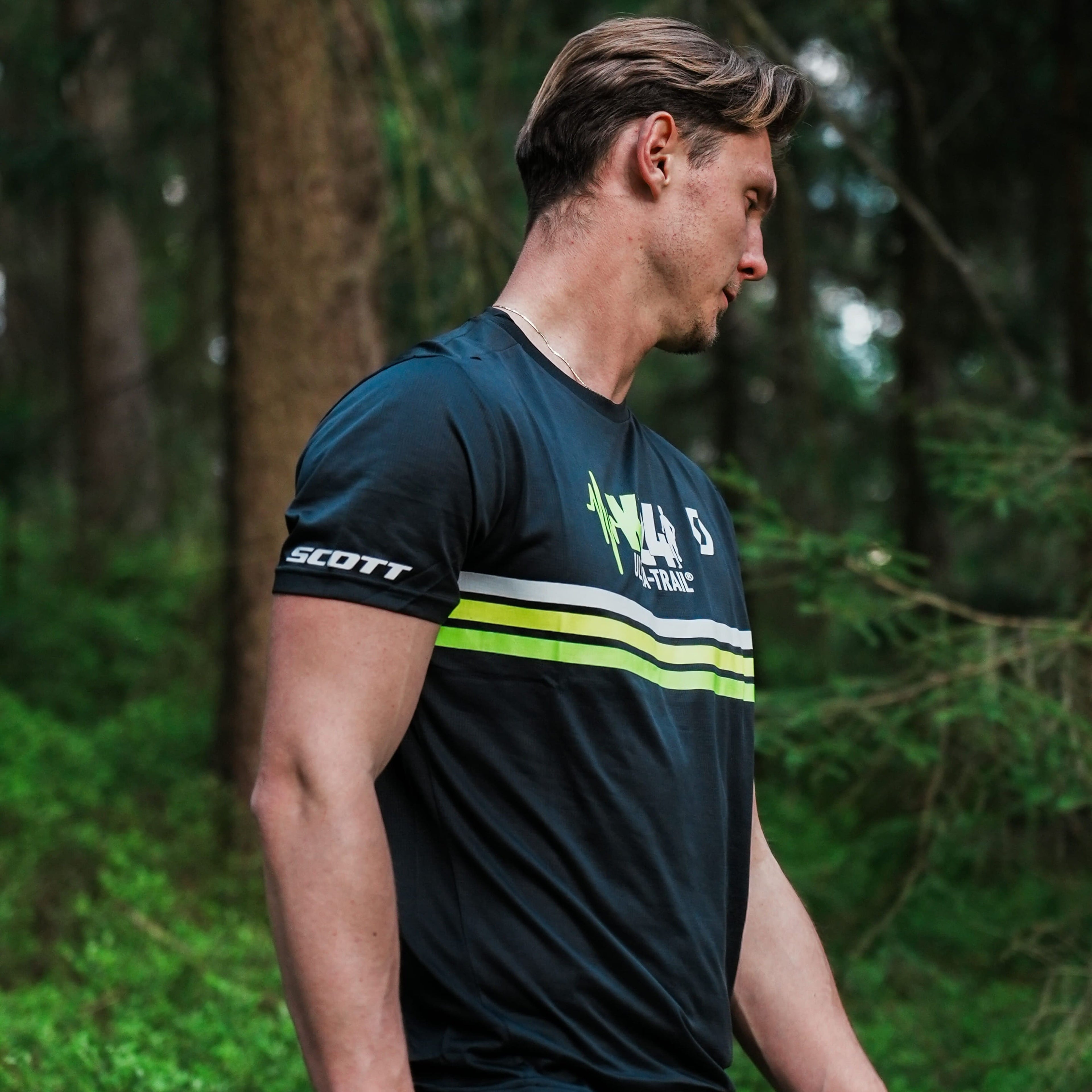 Man wearing a sports jersey with brand logos in a forest setting