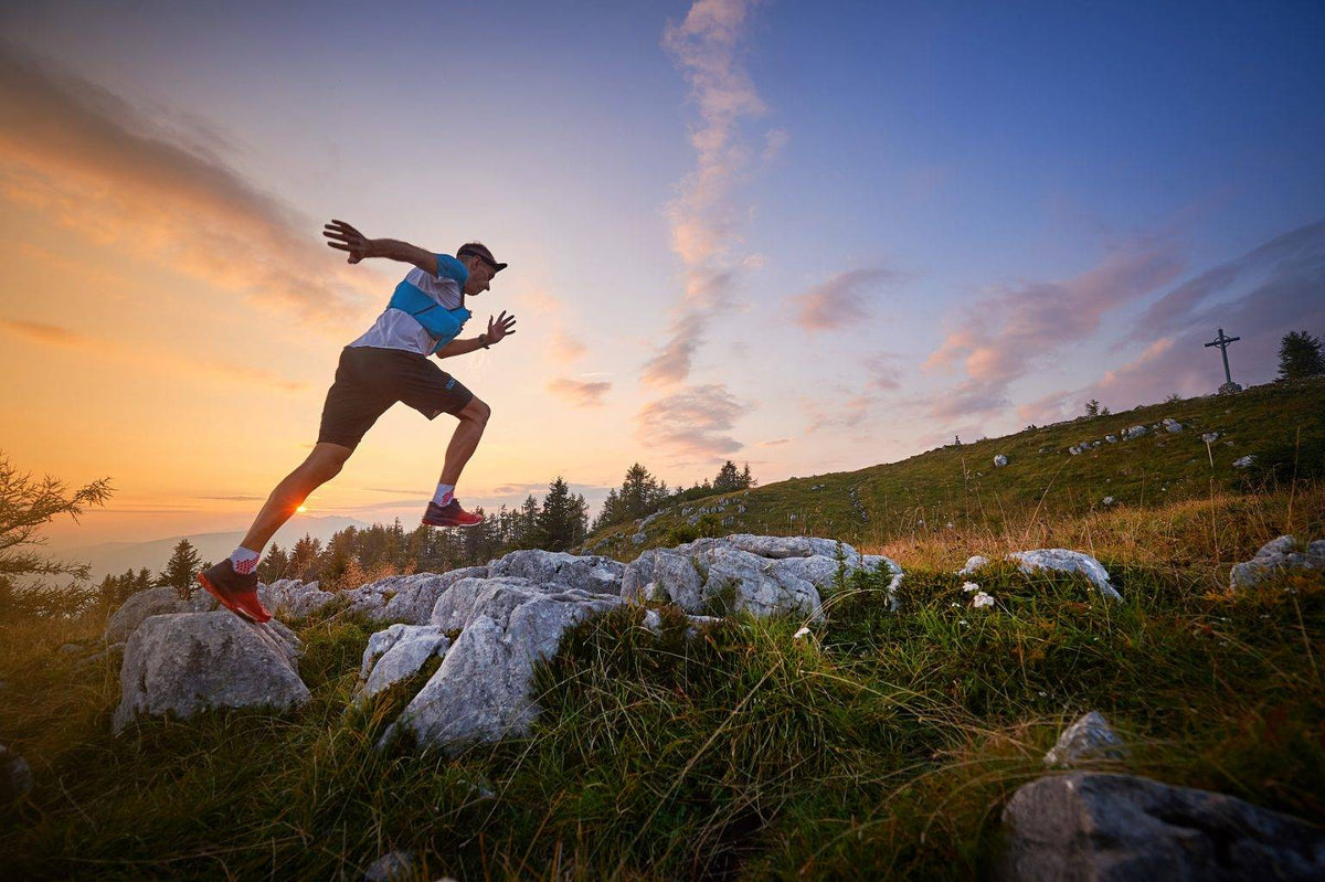 Person running on rocks with a scenic sunset background