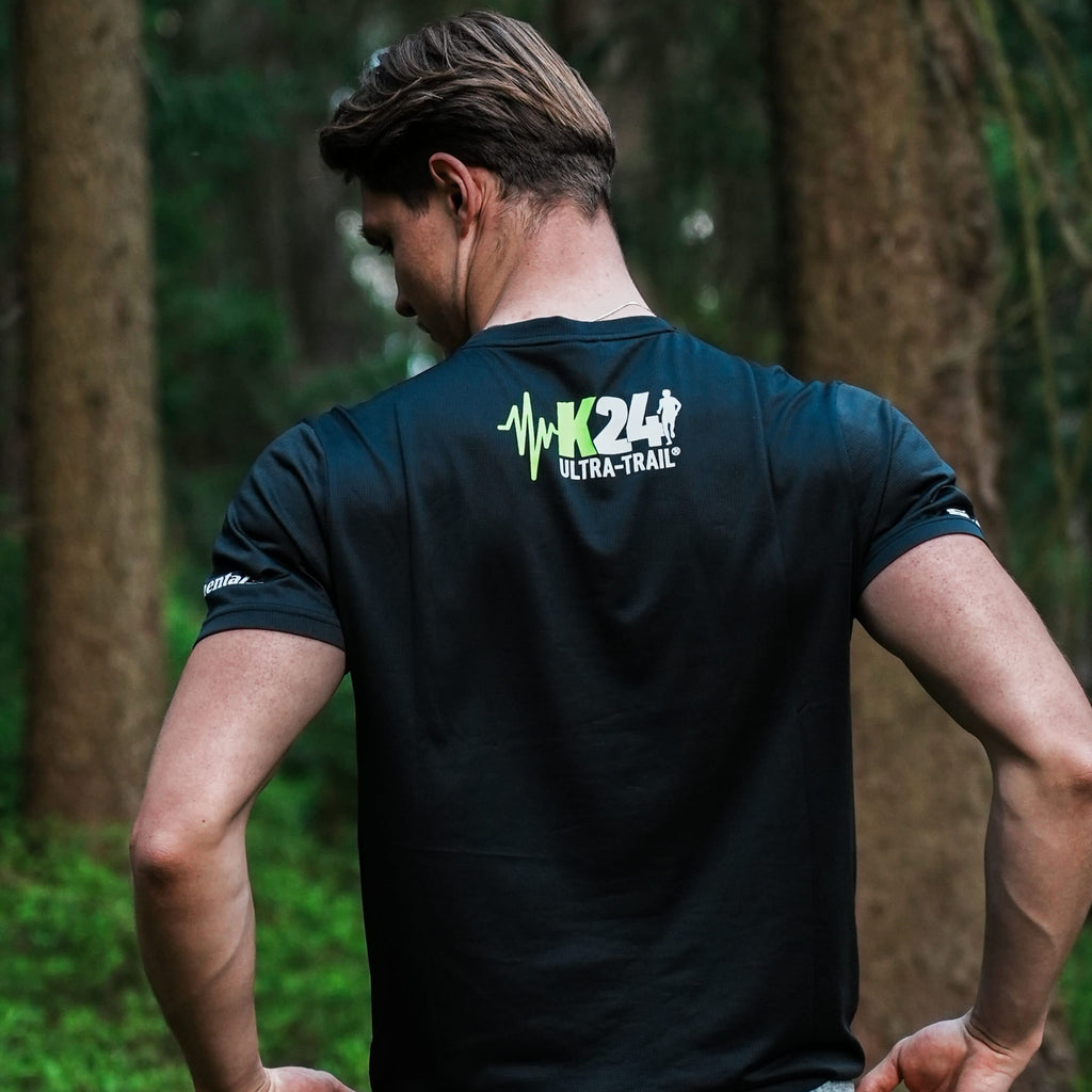 Person wearing a black t-shirt with a logo in a forest setting
