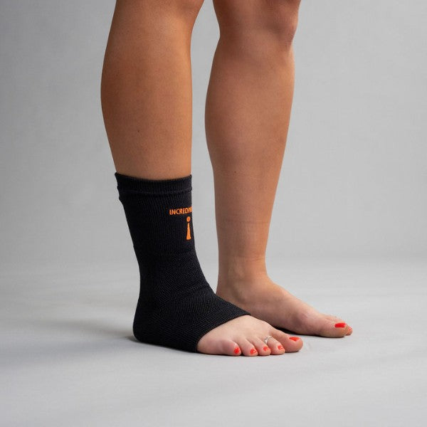 Person wearing a black ankle support brace with orange text on a gray background