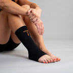 Person wearing black compression socks with orange text on a gray background