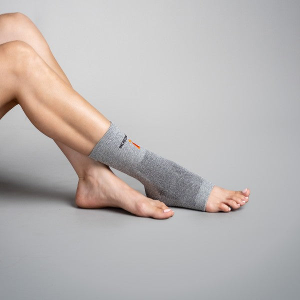 Gray ankle support brace on a person's foot against a gray background