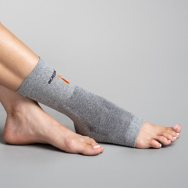 Gray ankle support brace on a person's foot against a gray background
