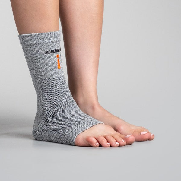 Gray ankle support brace worn by a person on a gray background
