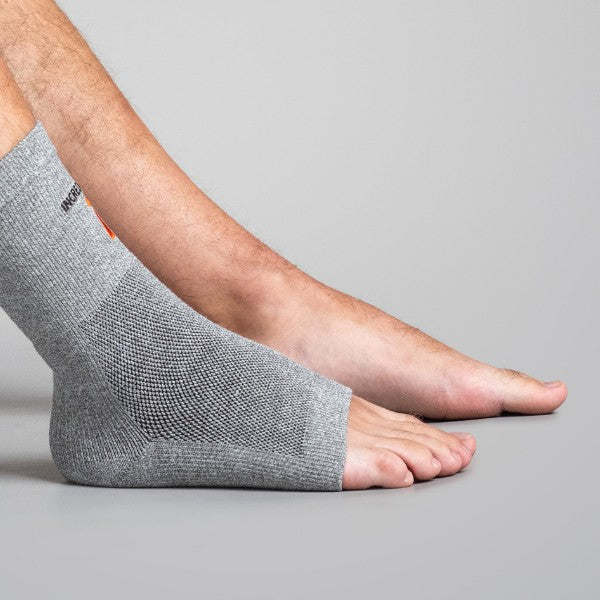 Gray ankle support brace on a person's foot against a gray background