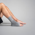Person wearing a gray ankle sock on a plain background