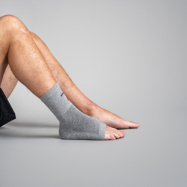 Person wearing a gray ankle sock on a plain background