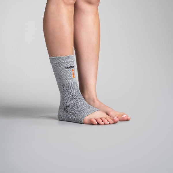 Person wearing a gray ankle support brace on a plain background