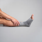 Person wearing a gray ankle sock on a plain background