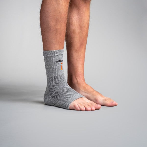 Person wearing a gray ankle support brace on a plain background