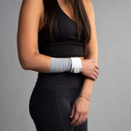 Person wearing a black sleeveless top and leggings with a gray bandage wrap band on a gray background
