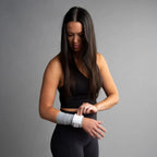 Woman wearing a gray bandage tape on her wrist against a gray background