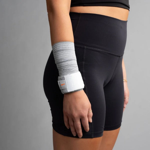 Person wearing black shorts and a gray bandage wrap on a gray background
