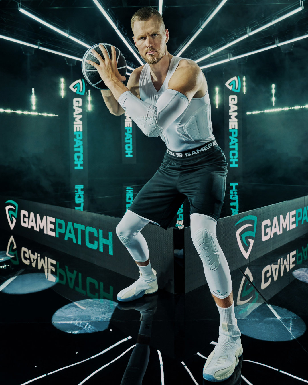 Man holding a basketball in an indoor sports arena with 'GamePatch' branding.