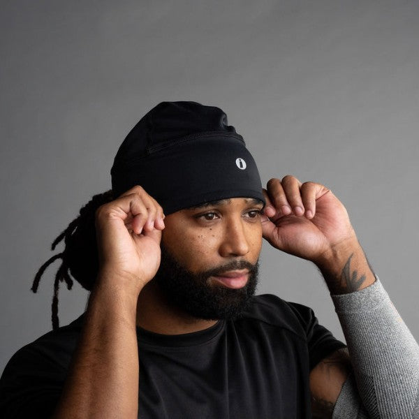 Man wearing a black beanie and black shirt against a gray background