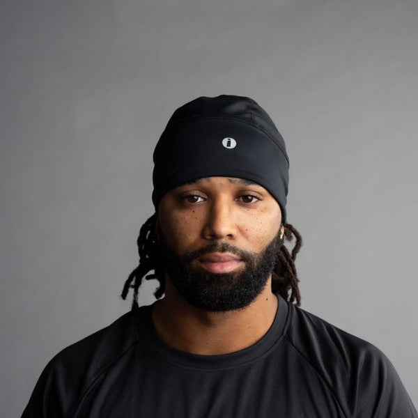 Man wearing a black beanie with a logo on a gray background