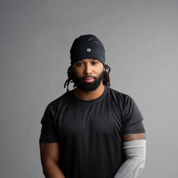 Man wearing a black beanie and t-shirt against a gray background