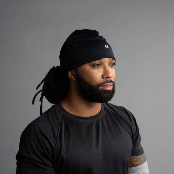 Man wearing a black beanie and black shirt against a gray background