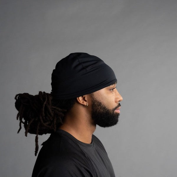 Man wearing a black headwrap against a gray background