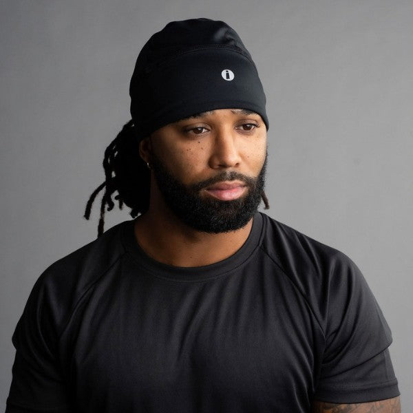 Man wearing a black beanie with a logo on a gray background
