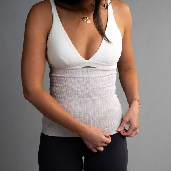Woman wearing a white compression body sleeve against a gray background