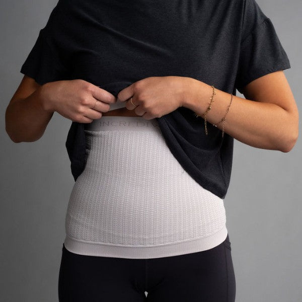 Person wearing a black shirt over a white compression garment on a gray background