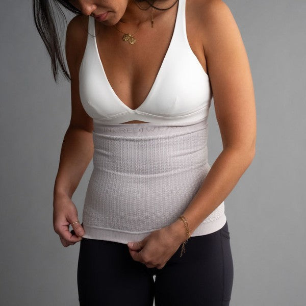 Woman wearing a white compression garment against a gray background