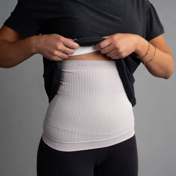 Person wearing a white compression garment with 'Incredibly' branding on a gray background