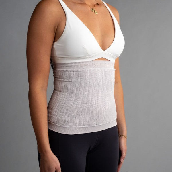 Person wearing a white compression garment against a gray background