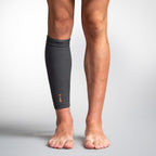 Person wearing a gray compression sleeve on one leg against a plain background