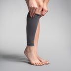 Person wearing a gray compression sleeve on their leg against a plain background