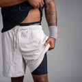 Person wearing a black shorts and white athletic outfit with visible branding on a gray background