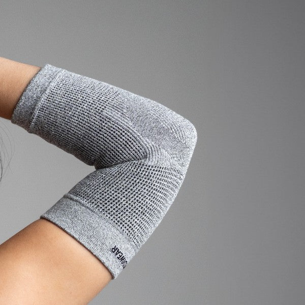 Gray elbow support on a person's arm against a gray background