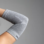 Gray elbow support on a person's arm against a gray background