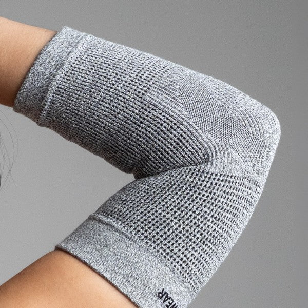 Gray elbow support on a person's arm against a gray background