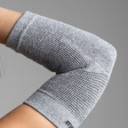 Gray elbow support on a person's arm against a gray background