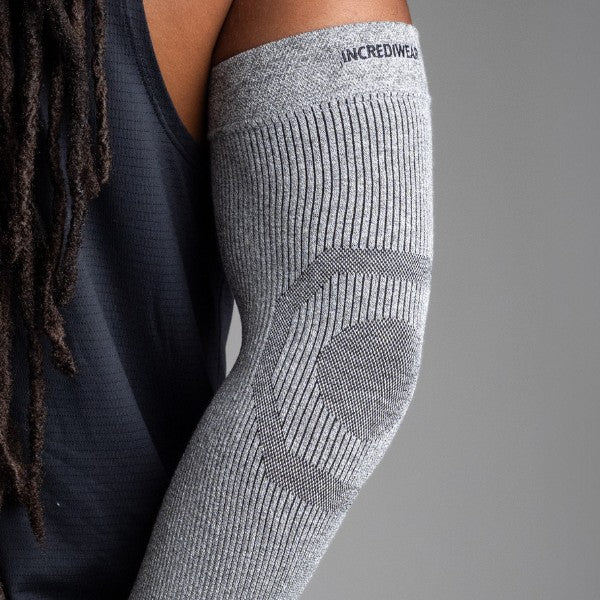 Gray compression sleeve on a person's arm with 'INCREDIWEAR' branding, against a neutral background.