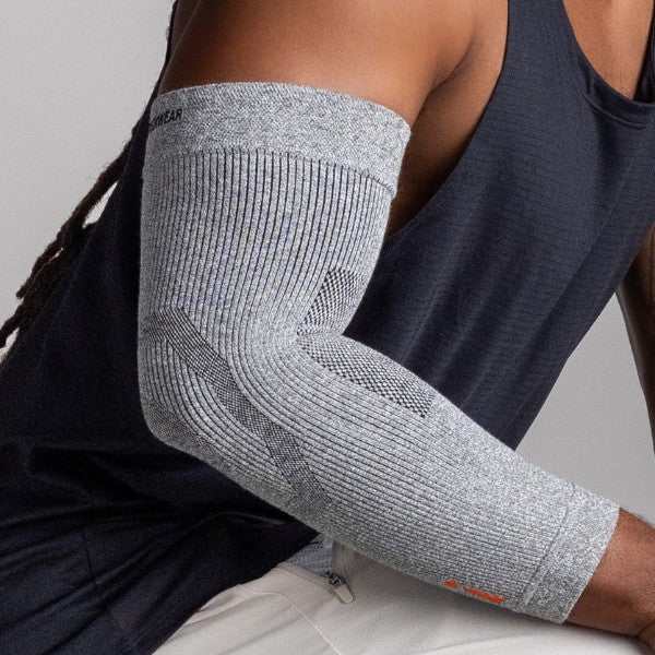 Person wearing a gray elbow support brace on a neutral background