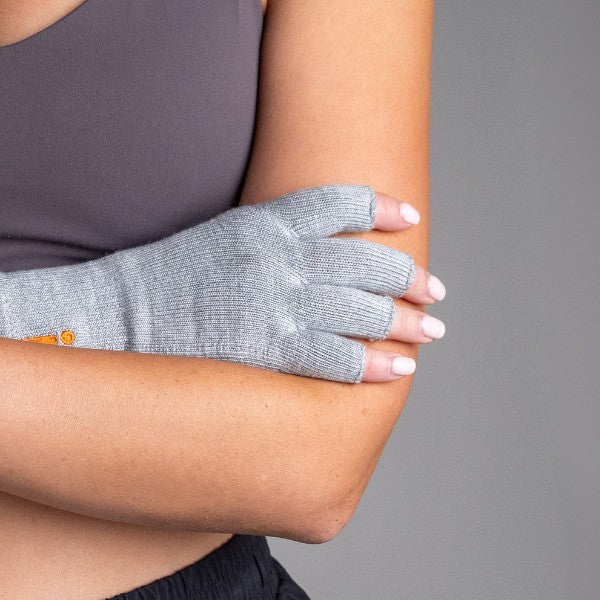 Person wearing a gray compression glove on one hand against a gray background