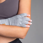 Person wearing a gray compression glove on one hand against a gray background