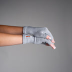Gray fingerless gloves worn by a person on a gray background