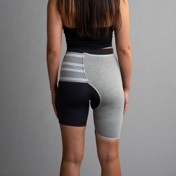 Person wearing a black and gray hip brace  on a gray background