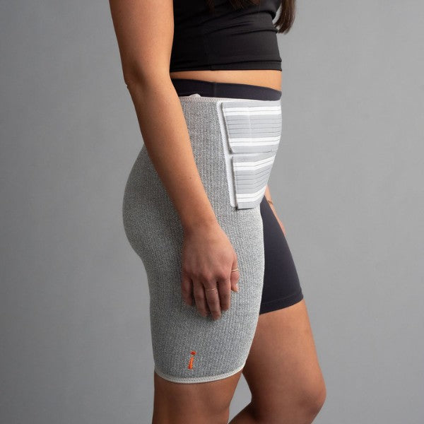 Person wearing a gray compression hip brace on a gray background
