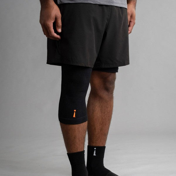 Person wearing black knee brace and shorts on a gray background