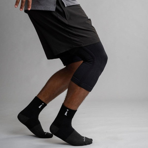 Person wearing black knee brace on a gray background