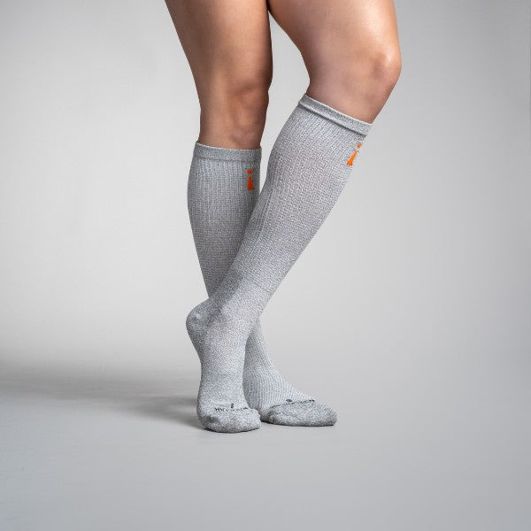 Gray knee-high socks with orange accents worn by a person on a gray background